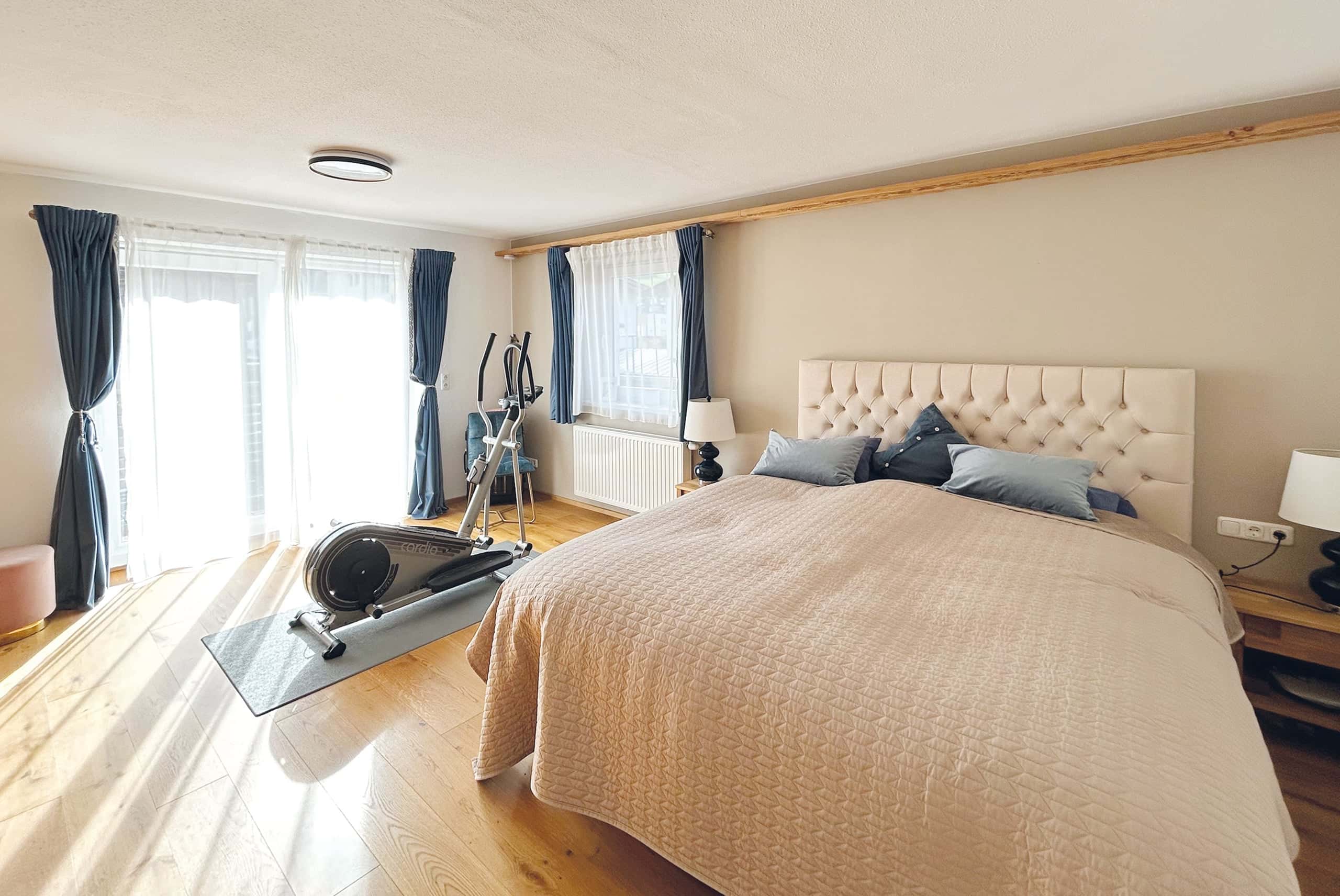 geräumiges Schlafzimmer mit indirekt beleuchteten Einbauschränken und Zugang zum Balkon